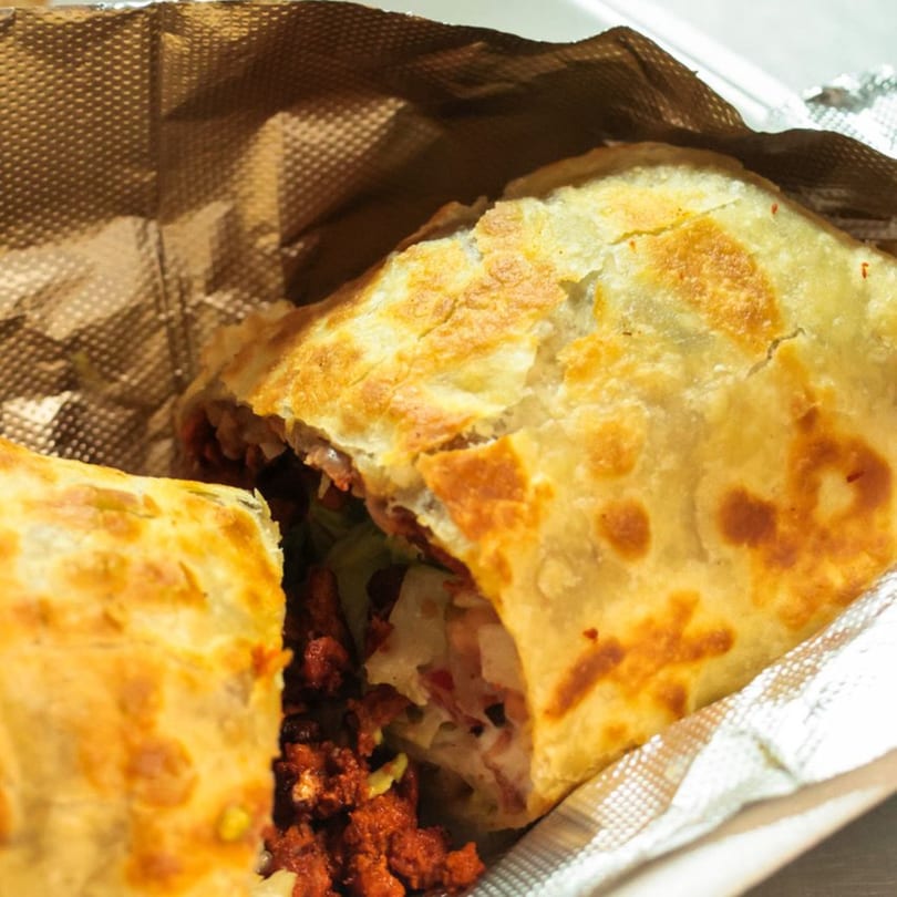 A golden-brown, crispy burrito, cut in half, revealing a savory filling of meat and cheese.